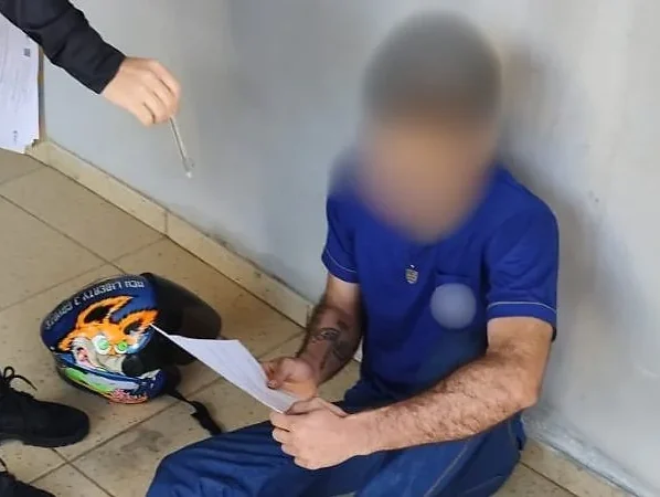 Suspeito da operação Opus Nequam sentado no chão