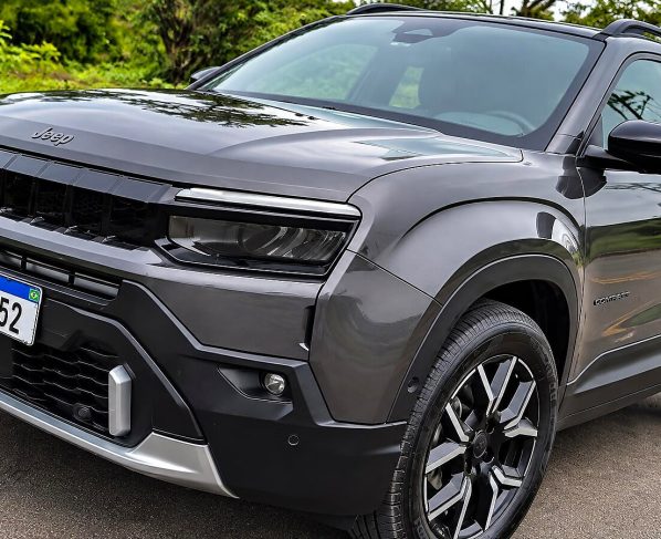 Jeep Avenger cinza estacionado em uma rua, visto de frente e pela lateral, com rodas pretas e detalhes prateados.